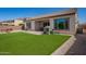 Spacious backyard featuring artificial grass, a covered patio, a barbecue, and a charming playhouse at 9678 W Patrick Ln, Peoria, AZ 85383