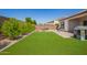 Lush backyard showcasing artificial grass, mature landscaping, a grill, seating, and a charming playhouse at 9678 W Patrick Ln, Peoria, AZ 85383