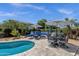 Desert backyard featuring a fire pit, lounge chairs, mature landscaping, umbrellas, outdoor seating, and a sparkling pool at 10359 E Los Lagos Vista Ave, Mesa, AZ 85209
