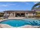 Backyard pool, patio, and outdoor kitchen with lush desert landscaping and a home with solar panels at 10359 E Los Lagos Vista Ave, Mesa, AZ 85209