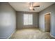 A cozy bedroom featuring a ceiling fan, a window with blinds, neutral carpet, and gray walls at 10548 W Crown King Rd, Tolleson, AZ 85353