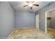 This bedroom features a ceiling fan, gray walls, carpet and a doorway to a walk-in closet at 10548 W Crown King Rd, Tolleson, AZ 85353