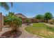 Well-maintained backyard with lush greenery, rock landscaping, and a brick-lined flower bed with verdant grass at 11303 E Pratt Ave, Mesa, AZ 85212