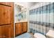 Bathroom with wood cabinets, a shower and tub combination with patterned curtain, and a framed mirror at 1640 E Augusta Ave, Chandler, AZ 85249