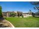 Lush backyard with manicured lawn, patio, palm trees and a home with neutral colored stucco at 1804 W Magdalena Ln, Phoenix, AZ 85041