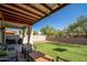 Spacious backyard featuring an artificial lawn, wood fence, and covered patio at 18401 W Westfall Way, Surprise, AZ 85374