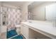 Bright bathroom with a shower/tub combo, white vanity, and blue rugs at 18401 W Westfall Way, Surprise, AZ 85374