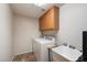 Functional laundry room featuring tile flooring, washer, dryer, upper wood cabinets, and sink at 1922 E Everett Dr, Phoenix, AZ 85022