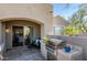 Covered patio with built-in grill, stone pavers, comfortable seating, and an arched entry to the home's interior at 19475 N Grayhawk Dr # 1039, Scottsdale, AZ 85255