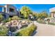 Beautiful water feature with rocks and landscaping outside a gray condo building against a clear blue sky at 19475 N Grayhawk Dr # 1039, Scottsdale, AZ 85255