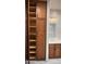 Open bathroom cabinet with several empty shelves, next to a marble sink and mirror, along with overhead lighting at 19475 N Grayhawk Dr # 1115, Scottsdale, AZ 85255