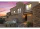 Inviting home exterior featuring a stone accent wall, desert landscaping, and soft illumination at dusk at 19475 N Grayhawk Dr # 1115, Scottsdale, AZ 85255