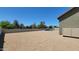 Open gravel backyard with an in-ground pool, mature trees, and clear skies at 21985 E Quintero Rd, Queen Creek, AZ 85142
