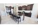 Well-lit kitchen featuring an island with barstool seating, dark wood cabinets, and stainless steel appliances at 21985 E Quintero Rd, Queen Creek, AZ 85142