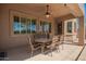 Cozy covered patio with an outdoor dining table, ceiling fan, and ample seating with large windows at 22304 N 104Th Ln, Peoria, AZ 85383
