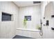 This shower has vertically stacked neutral-toned tile and black hardware, along with built-in shelving at 2353 N 51St Pl, Phoenix, AZ 85008