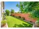 Well-manicured backyard with synthetic grass, a brick wall, and green landscaping offering a private outdoor space at 2611 S Quaintance St, Gilbert, AZ 85295