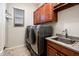 Laundry Room boasts washer and dryer, sink, wood cabinets, and light gray walls at 2611 S Quaintance St, Gilbert, AZ 85295