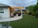 A backyard features artificial grass, a covered patio with furniture, and decorative string lights overhead at 2910 S Olivewood --, Mesa, AZ 85212