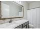 Bathroom vanity boasts double sinks, stone backsplash, framed mirror, and shower with patterned curtain at 3280 E Coconino Dr, Gilbert, AZ 85298