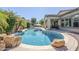 Backyard oasis with pebble tec pool, large rock features, covered patio, mature landscaping, and blue umbrella at 3280 E Coconino Dr, Gilbert, AZ 85298