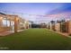 Expansive backyard featuring manicured lawn, overhead string lights, covered patio and privacy fence at 3604 E Derringer Way, Gilbert, AZ 85297