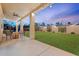 Relaxing covered patio with ample seating overlooking a spacious lawn, enhanced by ambient string lights at 3604 E Derringer Way, Gilbert, AZ 85297