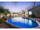 Stunning backyard pool with rock waterfall features, palm trees, and ambient lighting, creating a serene oasis at 3604 E Derringer Way, Gilbert, AZ 85297