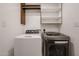 Well-organized laundry area with side by side appliances and shelving above at 4202 E Catalina Dr, Phoenix, AZ 85018