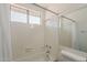 Bathroom with a white tiled shower/tub combination with a window and grab bars at 4627 E Mcneil St, Phoenix, AZ 85044