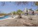 Backyard view of pool with slide and home with light tan exterior, landscaped with trees and decorative brick at 4627 E Mcneil St, Phoenix, AZ 85044
