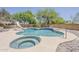 Backyard featuring an in-ground pool and attached hot tub, surrounded by lush landscaping and a brick wall at 4627 E Mcneil St, Phoenix, AZ 85044