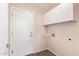 A functional laundry area with storage cabinets, tile floor, and a door for convenient access at 4911 E Holmes Ave, Mesa, AZ 85206