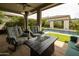Inviting covered back patio with comfortable seating, a fire pit, and lush pool area, ideal for outdoor living at 5515 S Caisson Way, Mesa, AZ 85212