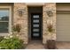 Stunning stone entryway with a modern black door and decorative potted plants at 5515 S Caisson Way, Mesa, AZ 85212