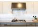 Close up of cooktop and backsplash showing stainless steel range hood in modern updated kitchen at 5515 S Caisson Way, Mesa, AZ 85212