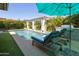 Backyard pool area with lounge seating, grill, and verdant landscaping at 5515 S Caisson Way, Mesa, AZ 85212