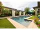 Beautiful pool with a modern waterfall feature, pergola, and lush landscaping, creating a serene outdoor oasis at 5515 S Caisson Way, Mesa, AZ 85212