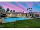 Tranquil backyard at dusk featuring a pool, artificial grass, desert landscaping, and modern pergola with ambient lighting at 6620 E Paradise Ln, Scottsdale, AZ 85254