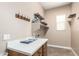 Functional laundry room with white counters, wooden cabinets, open shelves, and tile flooring at 6805 S Sapphire Way, Chandler, AZ 85249