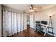 Cozy bedroom showcases hardwood floors, ceiling fan, floral curtains, and a comfortable workspace at 7110 N 28Th Dr, Phoenix, AZ 85051
