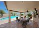 Covered patio with comfortable seating, ceiling fan, and a view of the sparkling pool and lush landscape at 7307 E Black Rock Rd, Scottsdale, AZ 85255