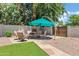 Outdoor lounge area with shade umbrella, surrounded by lush greenery and a beautifully landscaped backyard at 8936 N 80Th Pl, Scottsdale, AZ 85258