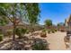 A spacious backyard features low-maintenance gravel landscaping, mature trees, and an outdoor grill at 9535 E Tupelo Ave, Mesa, AZ 85212