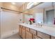 Bright bathroom featuring double sinks, neutral walls, a framed mirror, and a shower at 12910 W Junipero Dr, Sun City West, AZ 85375