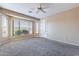 Spacious main bedroom with neutral paint, carpet flooring, ceiling fan, a large window and a walk in closet at 12910 W Junipero Dr, Sun City West, AZ 85375