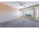 Spacious main bedroom with neutral paint, carpet flooring, ceiling fan and a large window at 12910 W Junipero Dr, Sun City West, AZ 85375