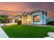Beautiful one story home with a well-manicured lawn, large windows and a two car garage at sunset at 1312 W Bartlett Way, Chandler, AZ 85248