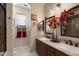 Elegant bathroom featuring a double sink vanity, decorative mirrors, and a glass-enclosed shower at 17541 W Statler Dr, Surprise, AZ 85388