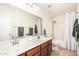 Bright bathroom featuring double sinks, a large mirror, and a shower/tub combination with a white shower curtain at 17753 W Columbine Dr, Surprise, AZ 85388